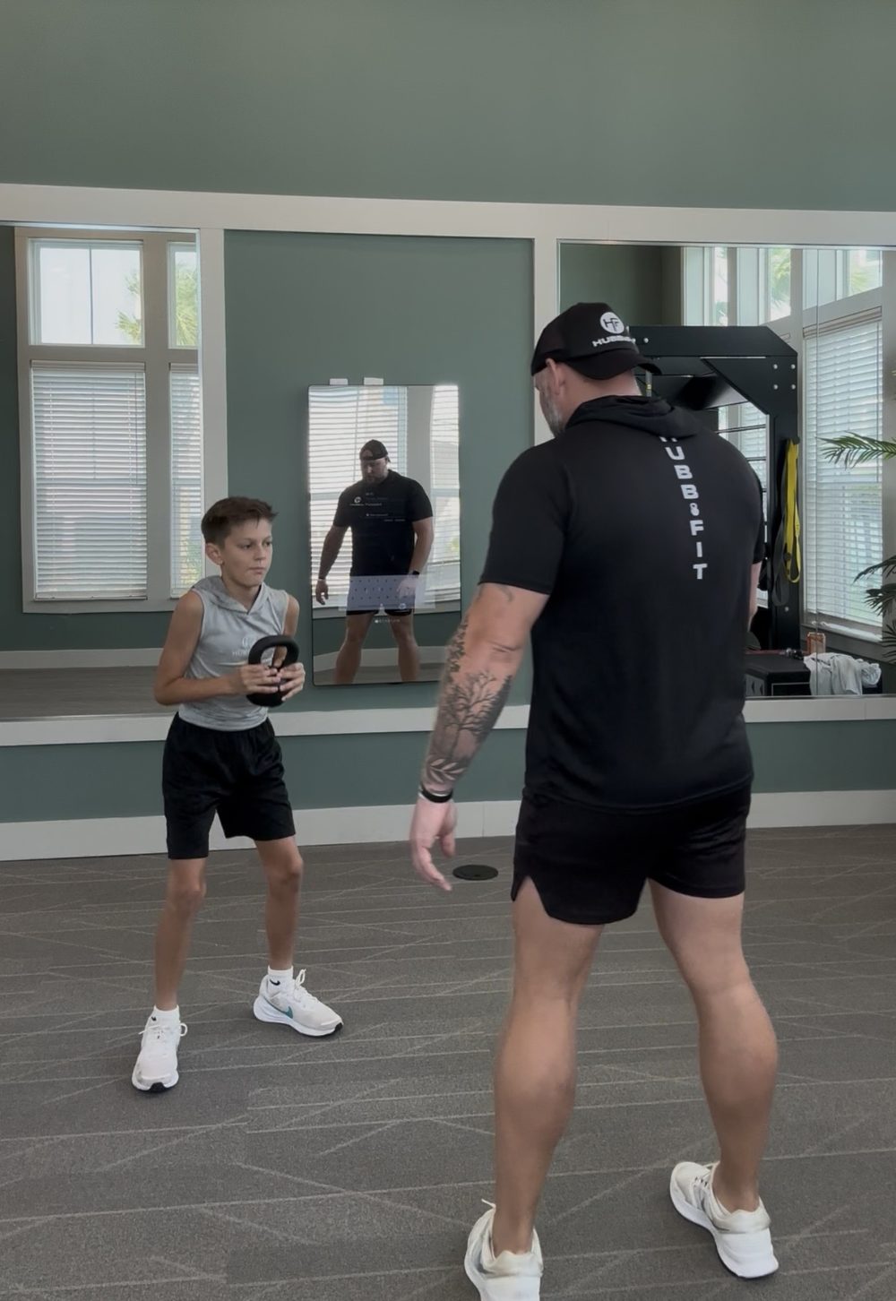 Ryan Hubble coaching a young athlete through an indoor kettlebell movement