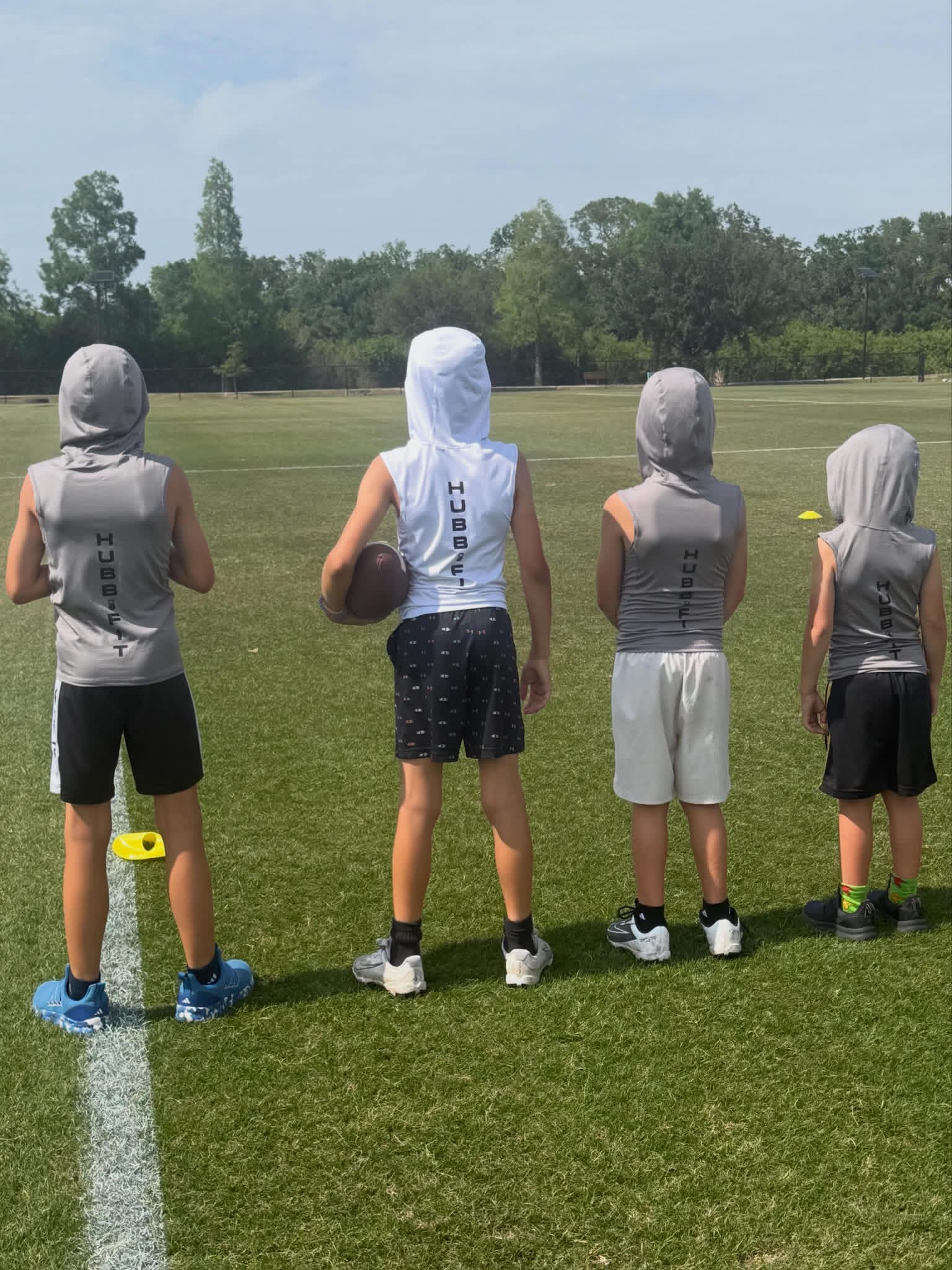 Four young athletes wearing Hubb.Fit training gear on a field